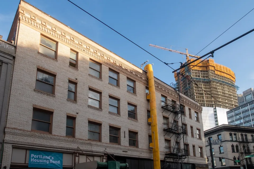 Brick building with high-rise under construction with yellow crane in background in downtown Portland, Oregon.